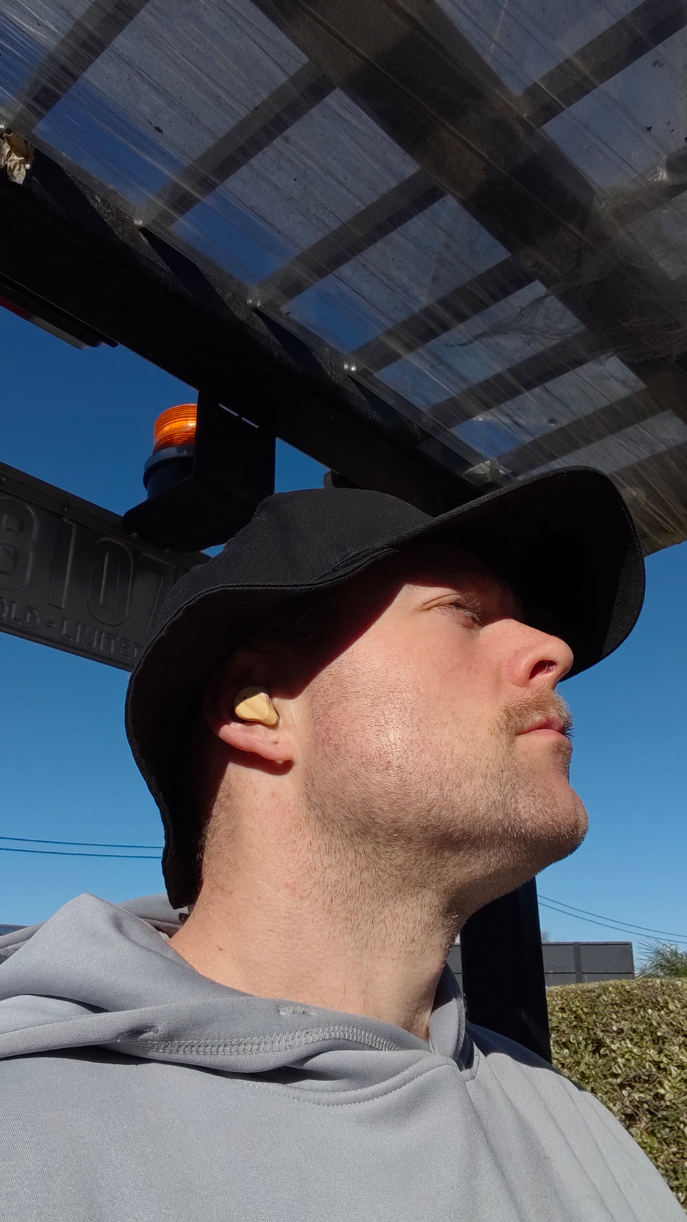 man wearing PureBuds Pro wireless bamboo earbuds outdoors on a forklift