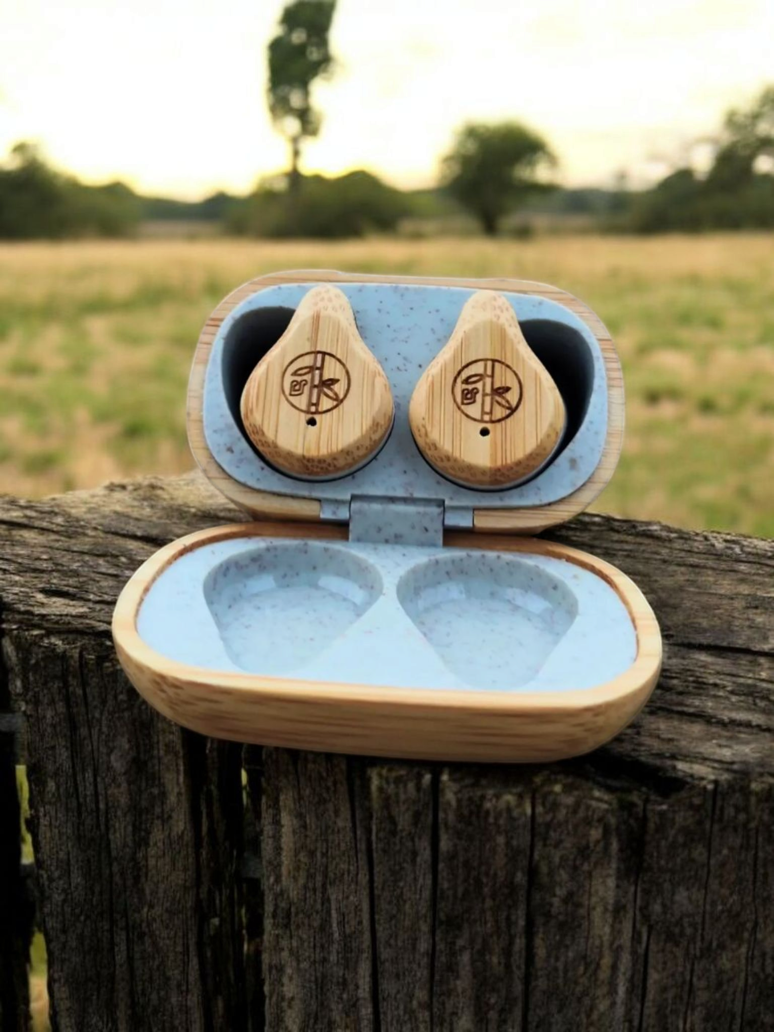 PureBuds wireless bamboo earbuds sitting on fence post