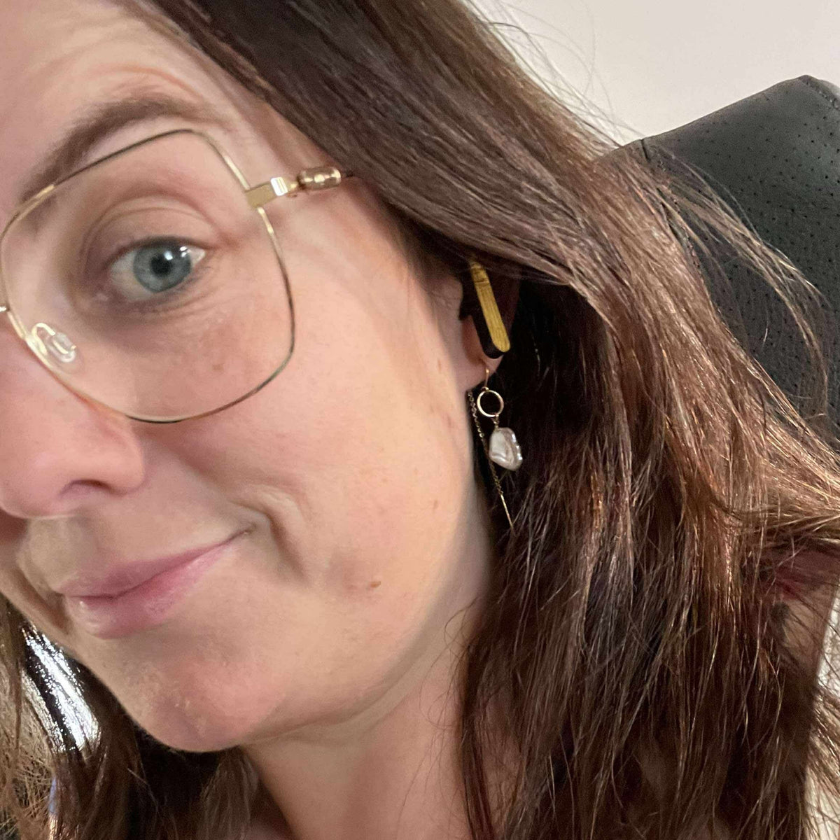 A woman wearing We Pure PurePods open-fit earbuds with a bamboo finish, showing a comfortable, non-intrusive fit.