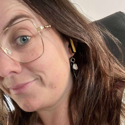 A woman wearing We Pure PurePods open-fit earbuds with a bamboo finish, showing a comfortable, non-intrusive fit.